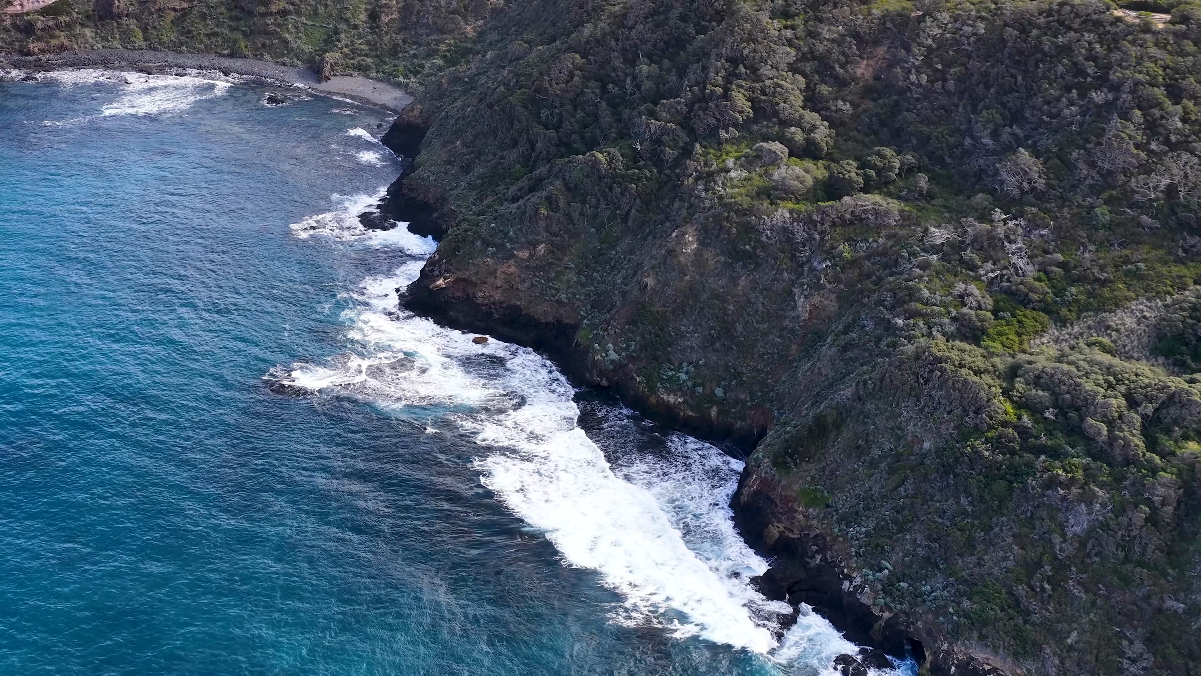 Aerial view of rugged coastal cliffs meeting turquoise ocean water along the California shoreline